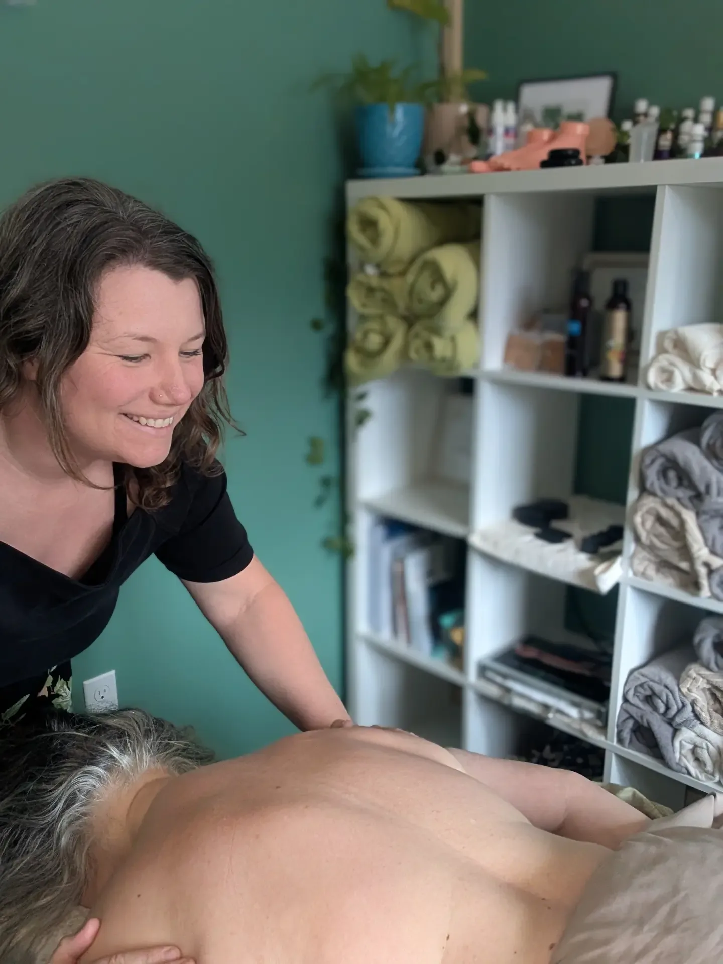 Haley Lorman smiling while giving a client a back massage in her Hebbville treatment room