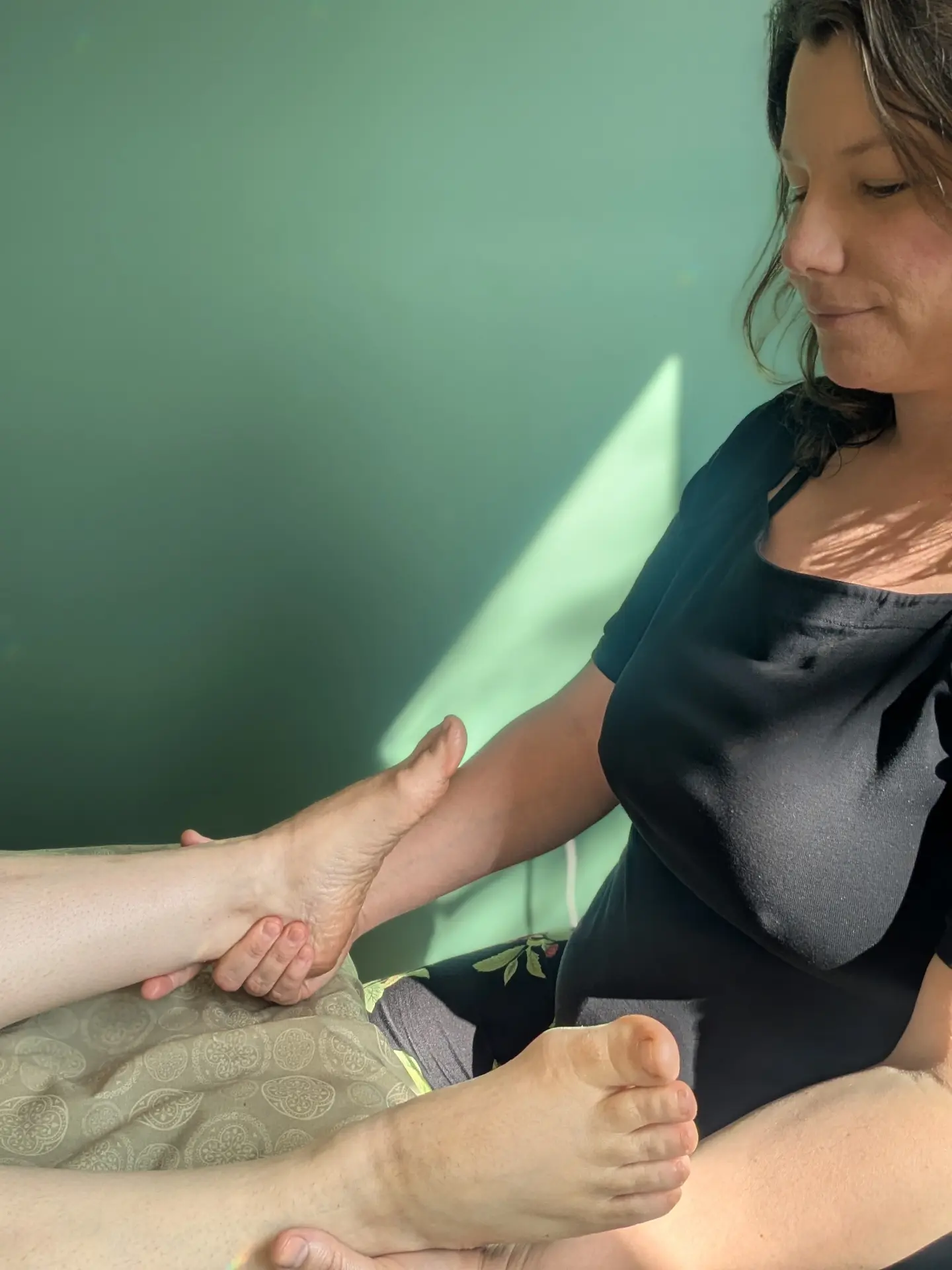 Haley Lorman holding a client's foot during a reflexology treatment in her Hebbville treatment room